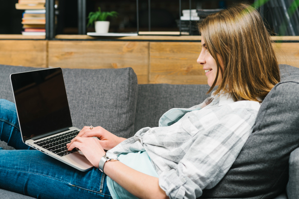 smiling woman using laptop sofa